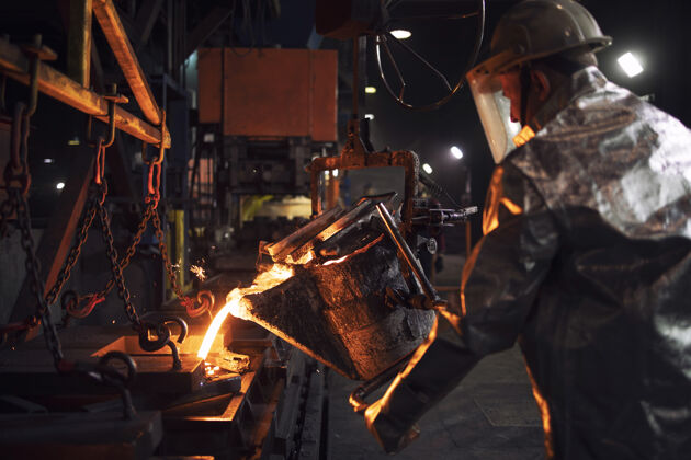 火花穿镀铝防护服的工人在铸造厂浇注钢水西装液体技术