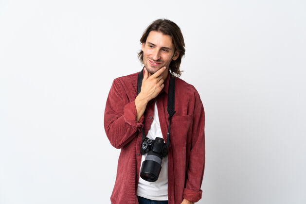 家伙一个年轻的摄影师站在白色的墙上 面带微笑地看着身边稍后设备人