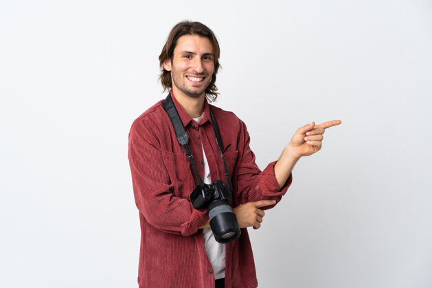 摄影师年轻的摄影师被隔离在白色的墙上 手指指向侧面产品快乐手势