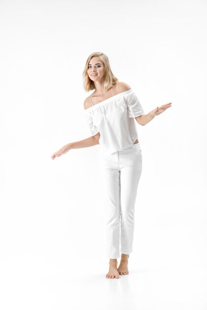 女孩美丽快乐的金发女人在白色衬衫和裤子的白色背景复制性感漂亮