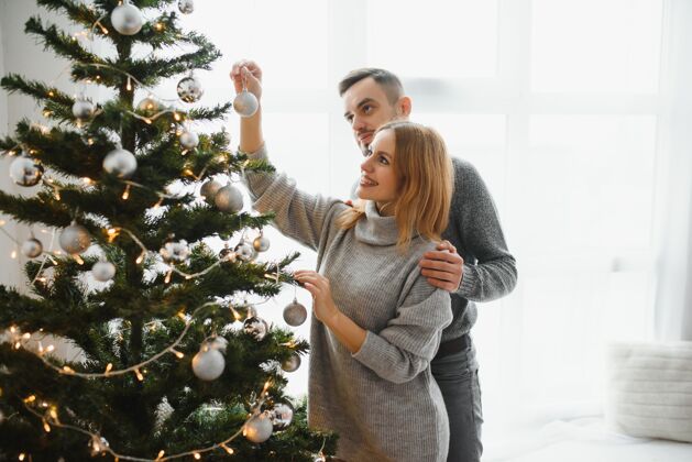 男人美丽的夫妇一起装饰圣诞树拥抱在一起女人