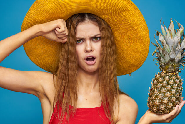 肖像戴着黄色帽子的女人 手里拿着菠萝 心情愉悦 生活方式 夏日水果蓝色背景季节感官年轻人