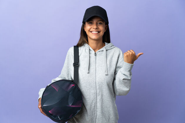 肖像年轻的运动女士拿着运动包指着侧面展示产品年轻人女孩运动员