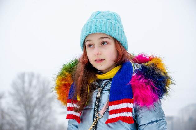 女性冬日少女的画像在她的温暖服装.青少年下雪天戴蓝帽子的女孩帽子雪时尚