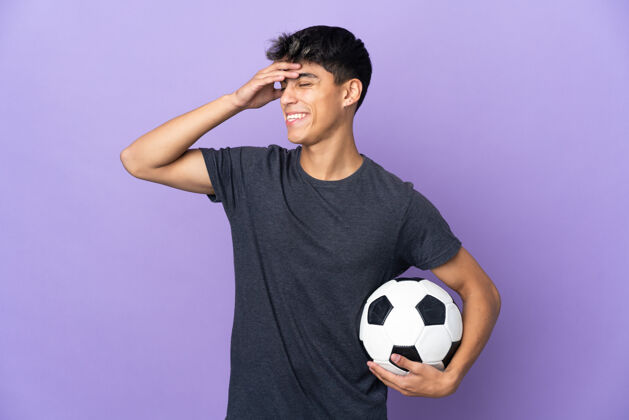 好年轻的足球运动员在孤立的紫色背景下笑了很多肖像快乐运动装