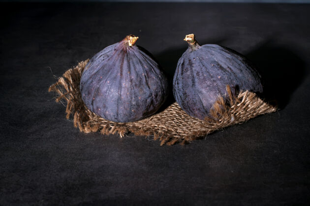 封闭两个成熟的紫色无花果躺在粗糙的布和混凝土顶上成熟吃有机