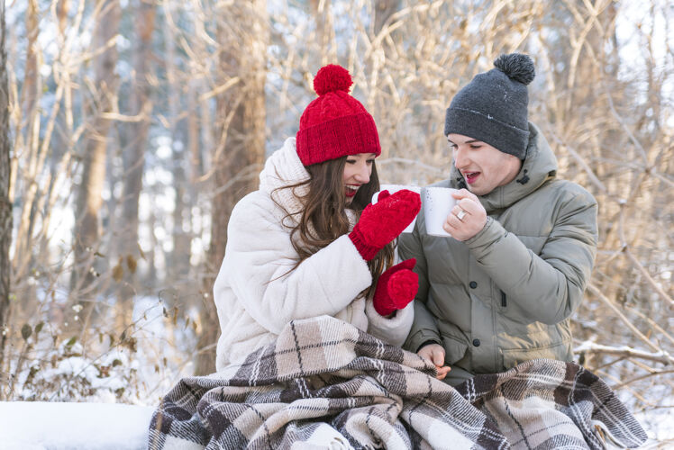 寒冷爱故事年轻冬季公园里的一对情侣裹着毛毯喝茶毯子浪漫关系