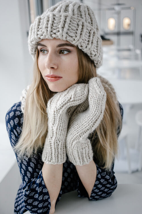 女人美丽可爱的女人 戴着针织冬季帽子和手套在咖啡馆的背景女孩混合针织