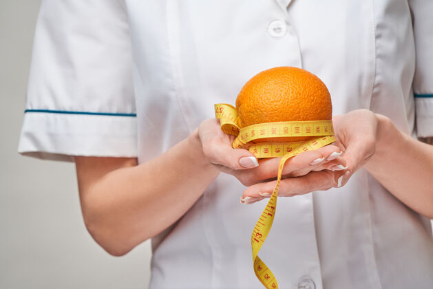 概念营养师医生健康的生活方式概念-持有有机新鲜橘子水果和卷尺免疫力喜欢水合作用