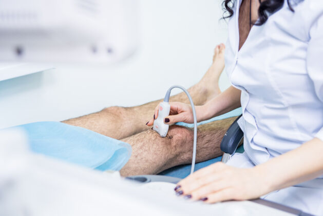 治疗医生用超声波扫描仪检查受伤的膝盖患者专家腿部