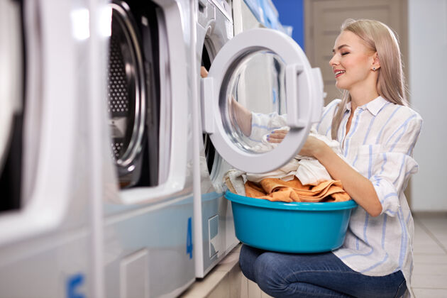 内做家务的女人-洗衣房.女将干净的衣物叠放在洗衣盆中 侧视图为正在洗衣服的女士房屋清洁 洗涤理念管家清洁家务