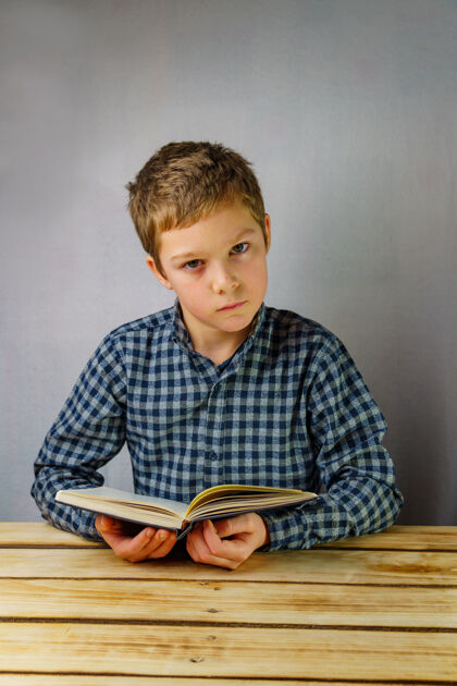 书籍穿着格子衬衫 手里拿着一本书的严肃男孩手垂直照片 学生打开兴趣