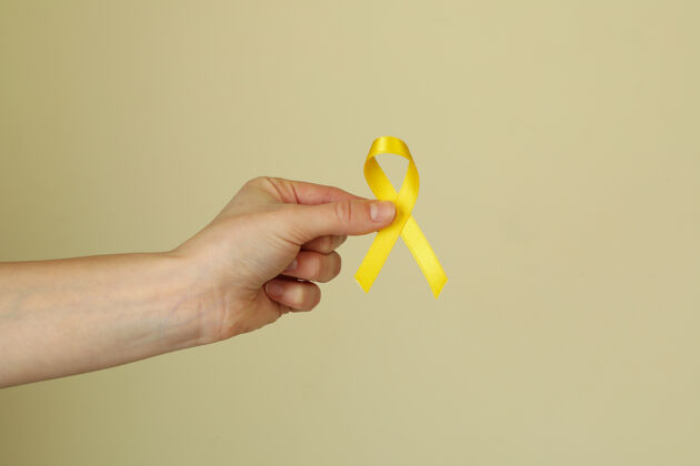 手米色背景上的女性手握儿童癌症意识丝带孩子慈善癌症