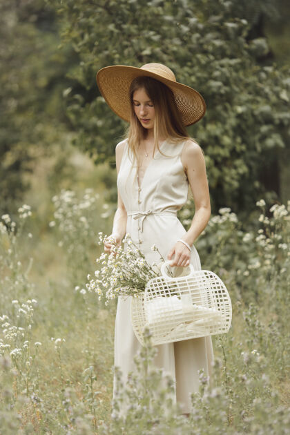 慢动作穿着时髦的女孩带着篮子穿过草地花年轻天生金发乡村收集帽子