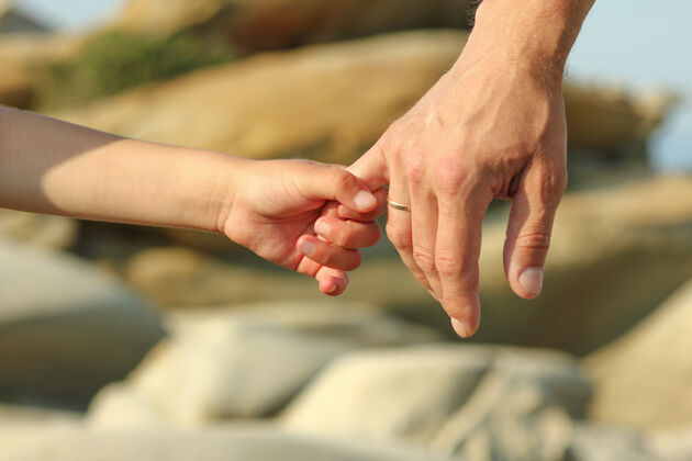 储藏父母握着一个小孩的手靠近石头成人安静接受