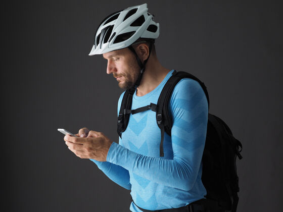 使用背着背包骑自行车的男子使用智能手机的画像骑格雷背景应用程序头盔个人资料