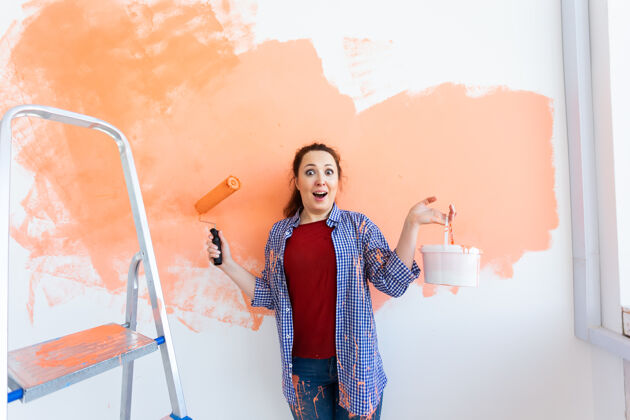 女士笑嘻嘻的女人用油漆粉刷家里的内墙重新装修 翻新女孩装修改善
