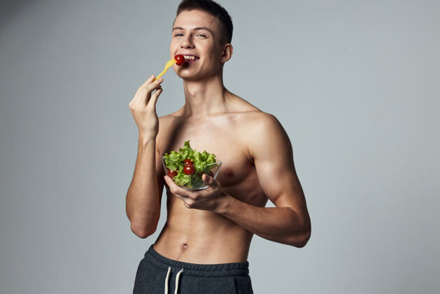 年轻有趣的运动家伙沙拉健康食品不规则的锻炼视图盘沙拉素食者二头肌