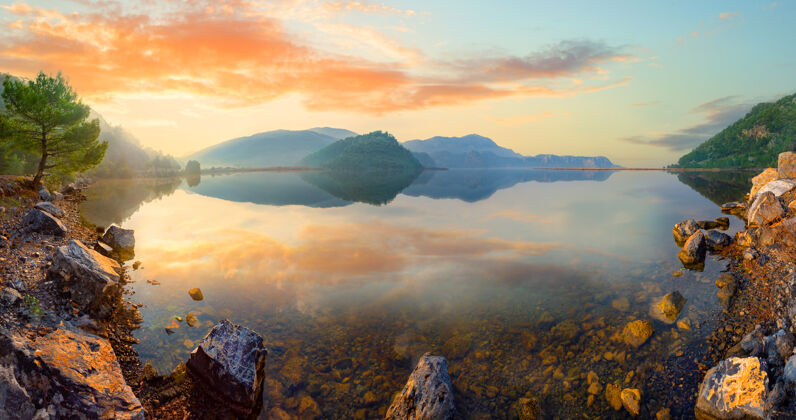 岩石日落时山湖和岩石海岸的全景图云景色季节