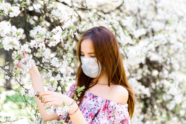 春天在樱花盛开的樱花树下 一个穿着白色上衣 戴着冠状病毒花朵面具的温柔女孩的特写镜头流行病开花自然