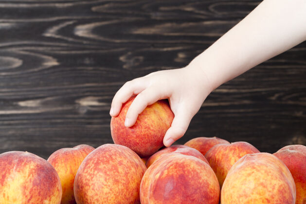 儿童大量新鲜柔软的桃子放在亚麻桌布上 特写 其中一个桃子被一个孩子捡了起来饮食食物市场