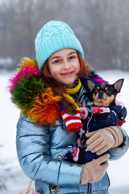 美丽冬日少女的画像在她的温暖服装.青少年穿蓝色衣服的女孩帽子女孩和吉娃娃在一起少年帽子天气