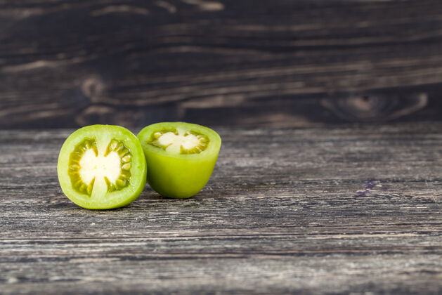 切割在一张黑桌子上切绿色番茄 一个蔬菜的特写新鲜叶子素食