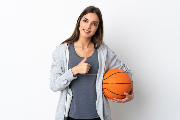 健康在白色背景下孤立地打篮球的年轻女子竖起大拇指运动微笑Ok