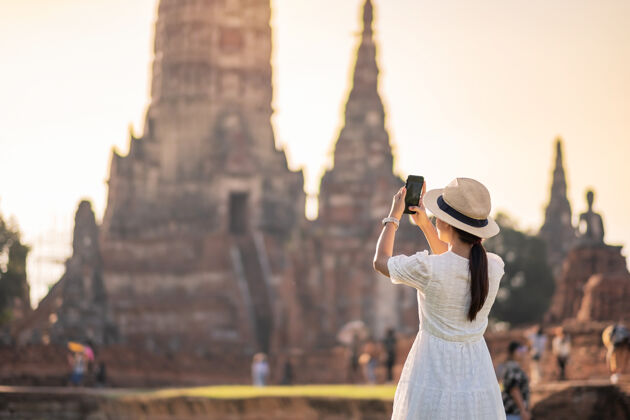 旅游在大城府历史公园watchaiwatthanaram寺庙参观期间 身着白色连衣裙的快乐旅游妇女通过手机拍照 夏季 独奏 亚洲和泰国旅游理念游览著名Take