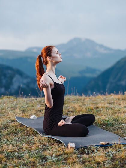 山穿着紧身裤的女人坐在地毯上冥想山里的大自然年轻美丽瑜伽