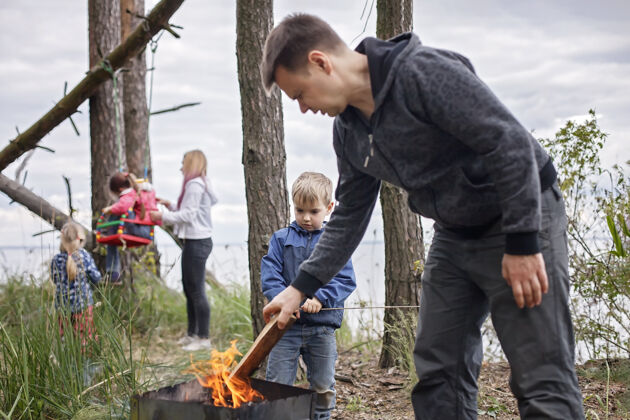小径新的正常逃生步骤 野生自然步行和家庭户外娱乐孩子们当父母在火旁煮奶酪和香肠的时候玩得开心 周末徒步旅行 生活方式新鲜空气营火篝火