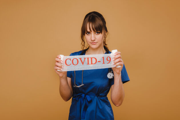 心脏病学一个戴着口罩 戴着手套 手持听诊器的医生手里拿着“covid-19”字样冠状病毒疾病流行病