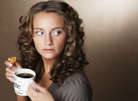 手手里拿着香浓咖啡的年轻女子浓缩咖啡美女马克杯