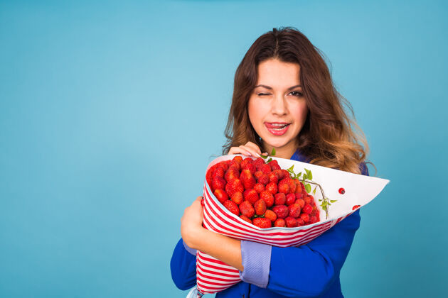 甜味拿着一束草莓的年轻女人植物水果健康