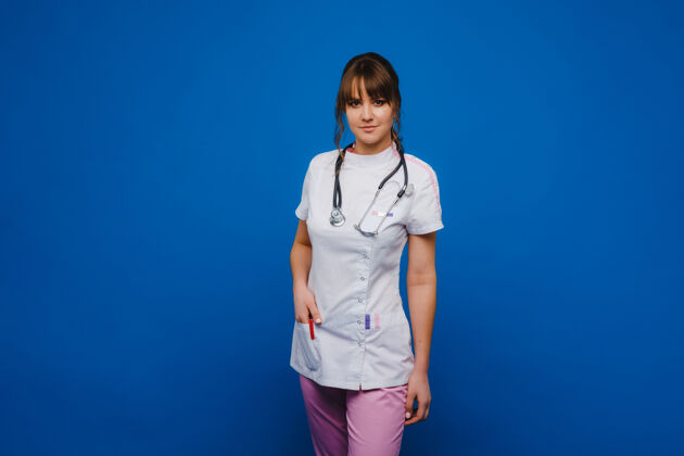 肖像年轻的女医生用听诊器隔离在蓝色背景上年轻亚洲人医学