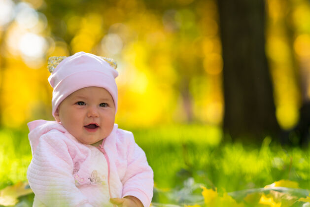 花园快乐微笑友好的小女婴坐在草地上 在秋天的林地在一个近距离肖像复制空间刺激内容吸收