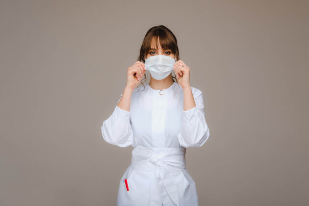 医学一个女医生戴着医用面罩站在一个灰色的背景上可爱女孩卫生