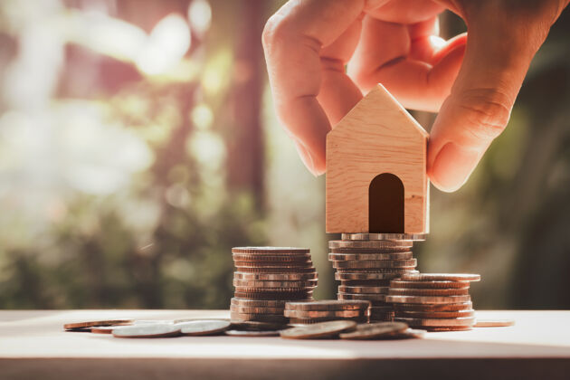 储蓄手牵手的房子模型放在堆叠硬币 储蓄买房 物业 抵押和房地产投资.物业房地产和金融概念经济现金房子