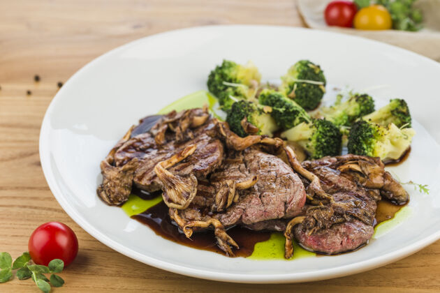 牛肉将牛肉 蘑菇和西兰花放在一个盘子里 放在一个浅色的木头表面上烤木头肉食物