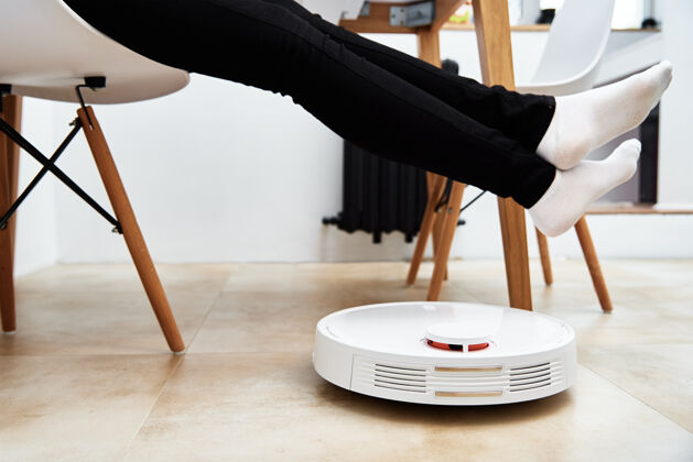 房子机器人吸尘器与家具一起在地板上工作 而女人休息现代智能家居清洁机器刷子