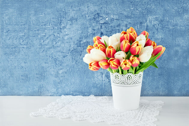 3月8日红色郁金香的花束在白色的花瓶上闪闪发光蓝色.假日 复制空间新鲜白郁金香明亮