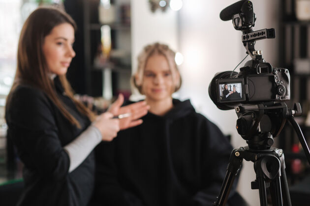 化妆刷女人在工作室为漂亮的金发女人化妆职业摄影数码相机