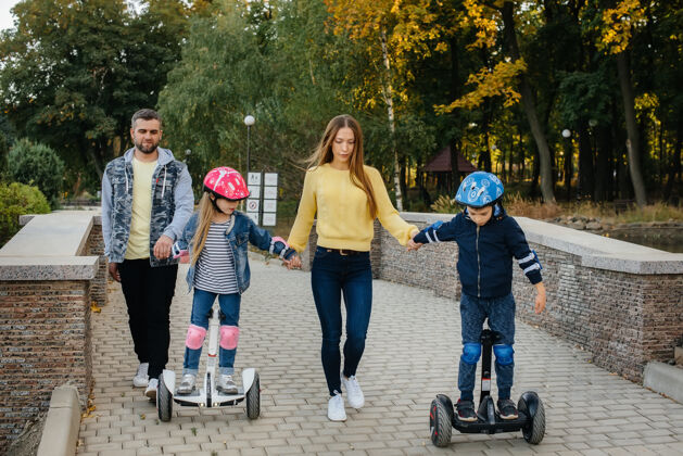 车辆一个快乐的大家庭骑着赛格威和电动踏板车在公园里一个温暖的秋日日落爱公共女孩