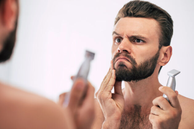 男子气概英俊的年轻人在街上刮胡子浴室.肖像一个时髦的裸体胡须男人在家里的镜子里检查他的脸早晨梳理优雅