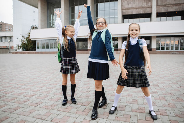 学生三个穿着裙子和高尔夫球衣的女学生在课程结束时欢欣鼓舞操场活跃乐趣