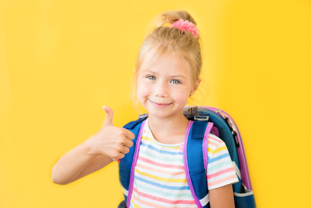 微笑黄色墙上一个带着背包微笑的小女生的画像学校学习女学生