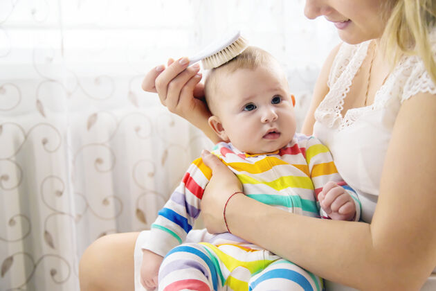女人妈妈正在给小婴儿梳头人类妈妈梳子