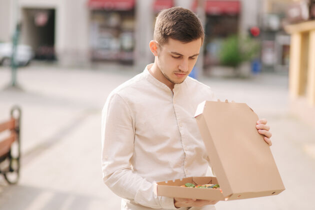素食主义者年轻人在户外打开披萨盒时感觉饿了情侣外卖楼梯