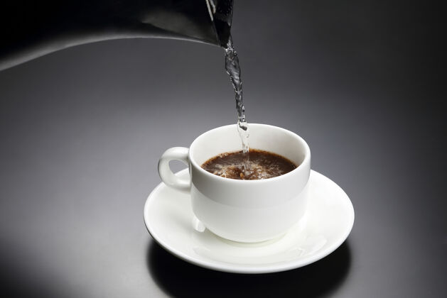液体把开水倒进一个白杯子里 再加上一个黑杯子咖啡热的喝酒热的盘子