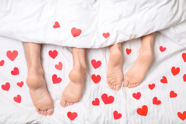 男人躺在床上的红心青年夫妇 顶视图浪漫舒适床单